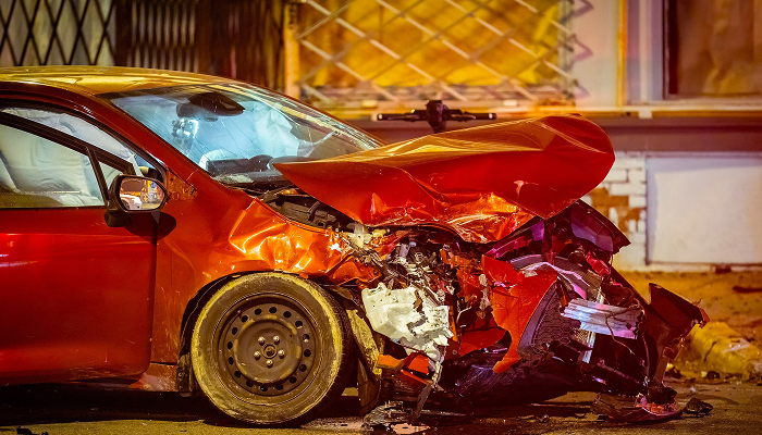 A red car with visible damage from a collision